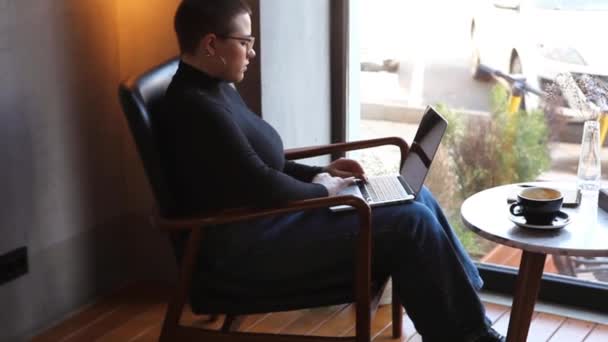 Une femme est assise dans un café et travaille dans une tablette.. — Video