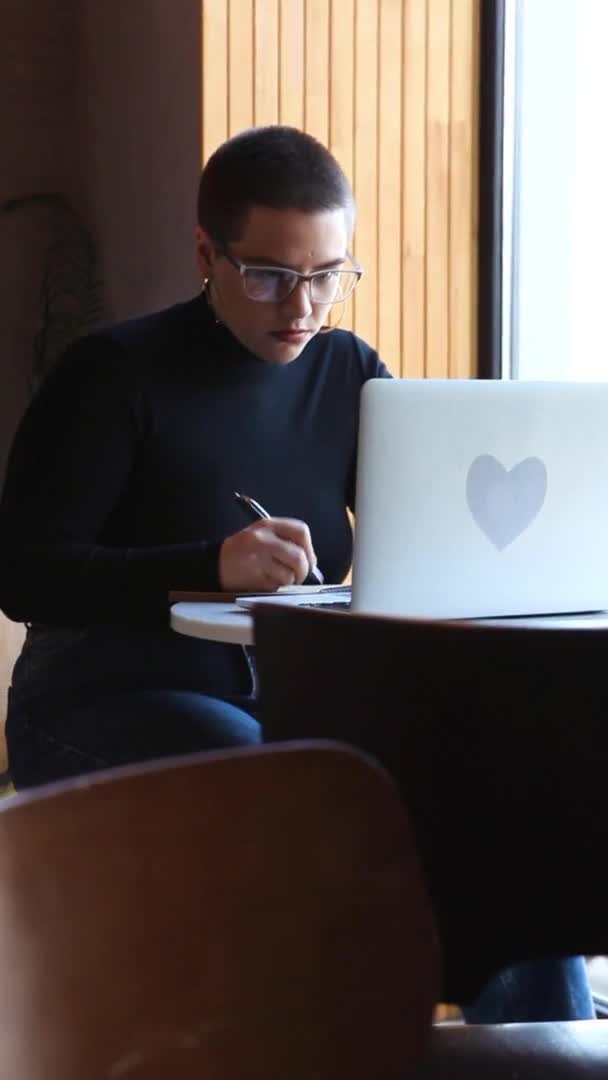 Egy nő ül egy kávézóban és egy tabletnél dolgozik.. — Stock videók