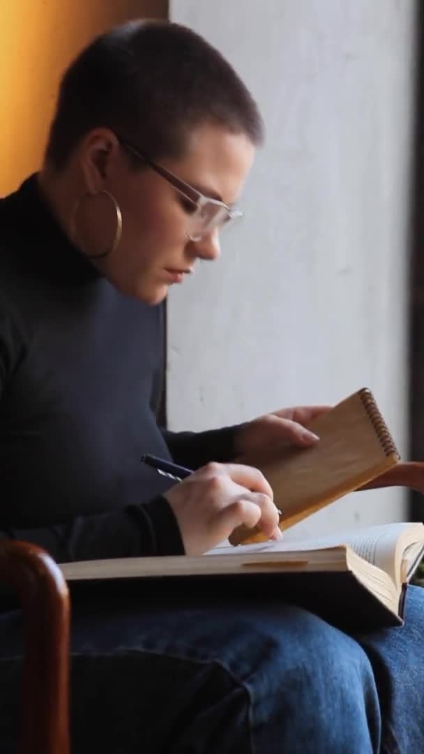 Eine Frau sitzt in einem Café und arbeitet an einem Tablet. — Stockvideo