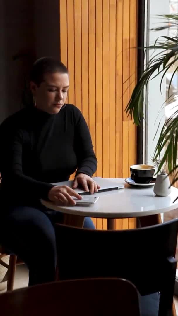 한 여자 가 카페에 앉아서 노트북으로 일하고 있습니다. — 비디오