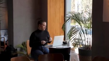 Bir kadın kafede oturur ve dizüstü bilgisayarda çalışır..