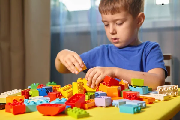 Un niño hermoso está jugando en casa con bloques de construcción. —  Fotos de Stock