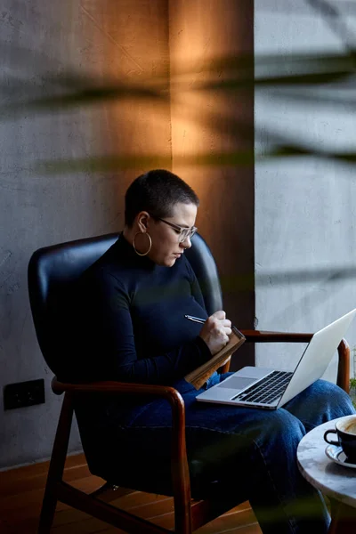 Une femme est assise dans un café et travaille dans un ordinateur portable. — Photo