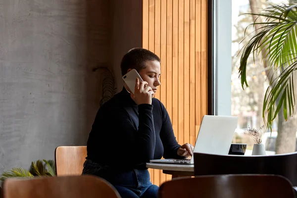 Een vrouw zit in een café en werkt op een laptop. Rechtenvrije Stockafbeeldingen