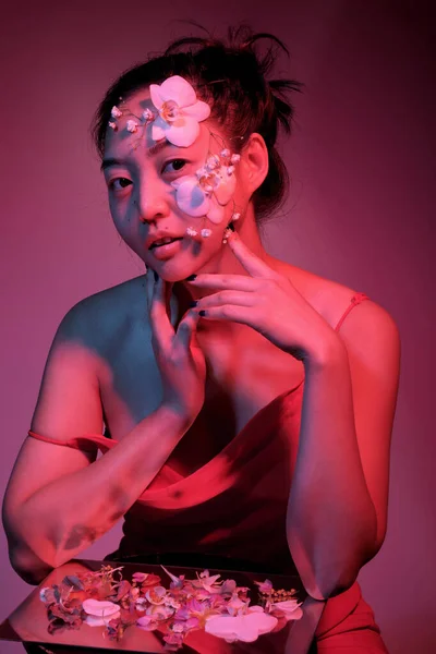顔に花を咲かせるアジアの女性 ロイヤリティフリーのストック写真