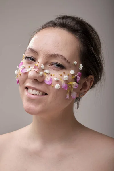 Vrouw met bloemen op haar gezicht Stockfoto