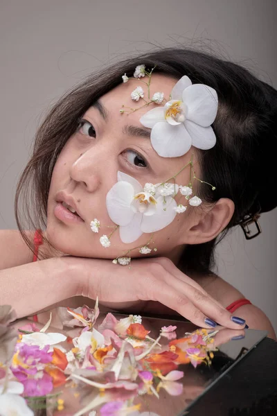 Азійка з квітами на обличчі. — стокове фото