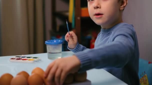 Маленький ребенок рисует пасхальное яйцо. — стоковое видео