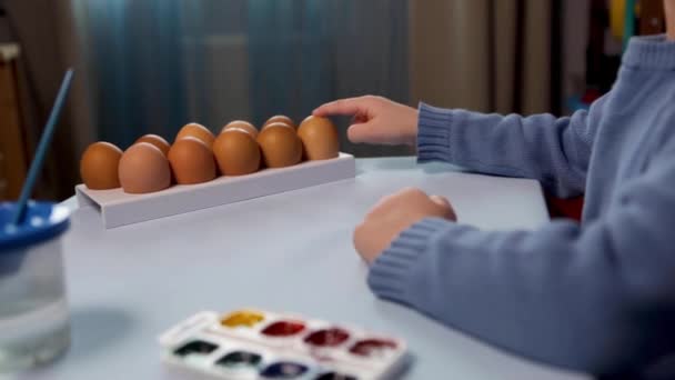 Ett litet barn målar ett påskägg. — Stockvideo