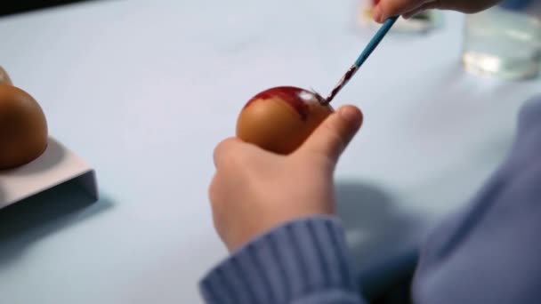 Un niño pequeño pinta un huevo de Pascua. — Vídeos de Stock