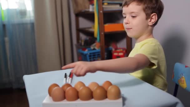 A little child paints an easter egg. — Stock Video
