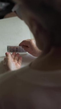 Yaşlı bir kadın tablet alır ve bir bardak su içer.