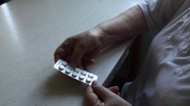 Yaşlı bir kadın tablet alır ve bir bardak su içer.