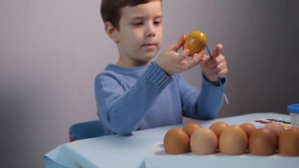 Un bambino dipinge un uovo di Pasqua. — Video Stock