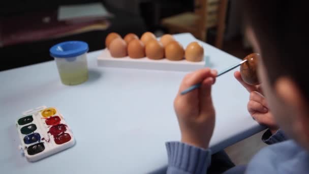 Un petit enfant peint un oeuf de Pâques. — Video
