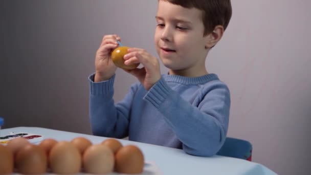 Un bambino dipinge un uovo di Pasqua. — Video Stock