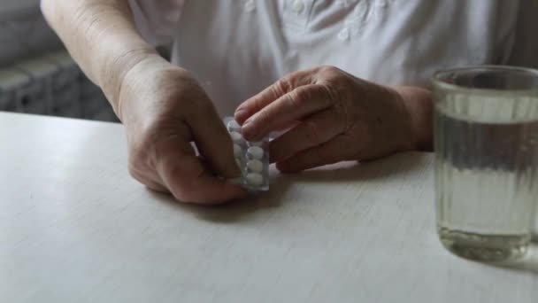 Starší žena si vezme tabletu a vypije sklenici vody — Stock video