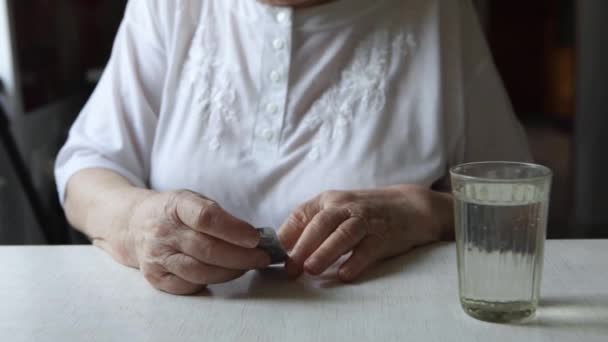 Пожилая женщина принимает таблетки и пьет стакан воды — стоковое видео