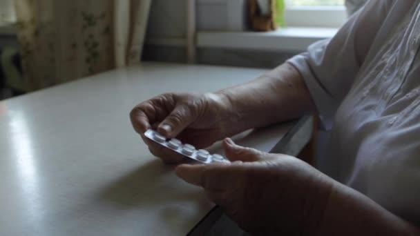 Starší žena si vezme tabletu a vypije sklenici vody — Stock video