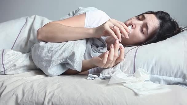 Kvinde liggende i sengen og begraver en dråbe forkølelse i næsen – Stock-video