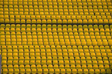 Yazın futbol sahasındaki insanlar için sarı koltuklu bir sürü sıra..