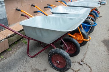 Kilitlenmiş birkaç metal bahçe el arabası kaldırımda ve sokakta duruyor..