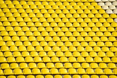 Yazın futbol sahasındaki insanlar için sarı koltuklu bir sürü sıra..
