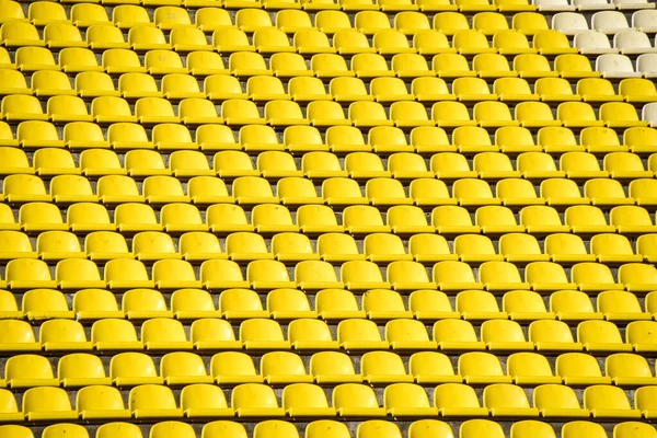 lots of rows with yellow seats for people on the football field in the summer.