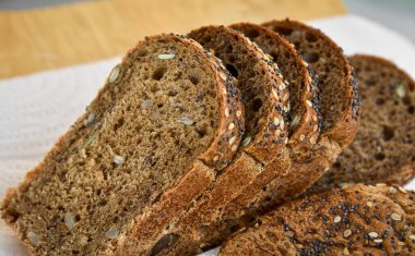 Dilimlenmiş çavdar ekmeği, ayçiçeği ve kırsal ahşap arka planda haşhaş tohumları. Sağlıklı yiyecekler hala hayat.