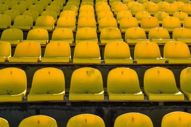 Yazın futbol sahasındaki insanlar için sarı koltuklu bir sürü sıra..