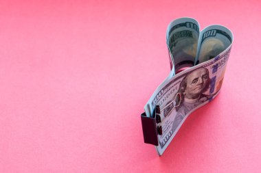 Kırmızı arka planda dolar banknotlarından yapılmış kalp.