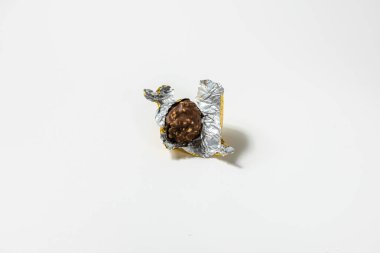 Beyaz arka planda yırtık ambalajlı tatlı, yuvarlak çikolatalı şeker..