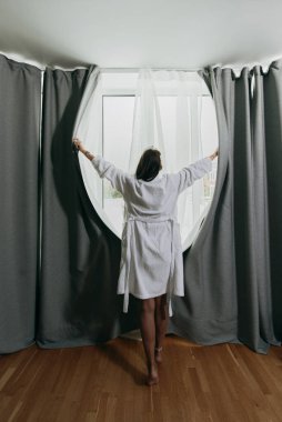 Perdeleri bornozlu bir kadın açıyor.