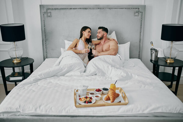 Пара влюбленных в халаты с завтраком в постели