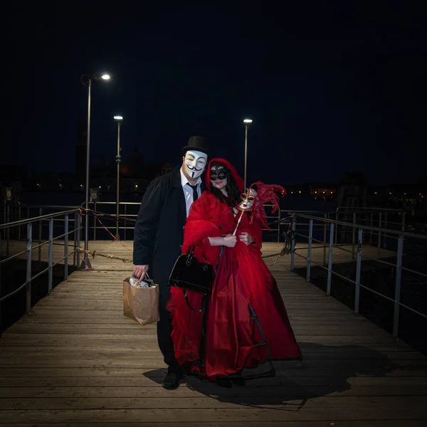ヴェネツィア イタリア 2022 夜にヴェネツィアのグランドキャナルで木製の桟橋に立つヴェネツィアのカーニバルの衣装の男と女 — ストック写真