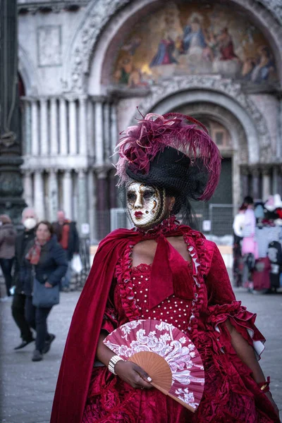 ヴェネツィア イタリア 2022 黒の帽子とベネチアン海軍で手のファンに紫色の機能を持つ赤いドレスの仮面の女性 — ストック写真