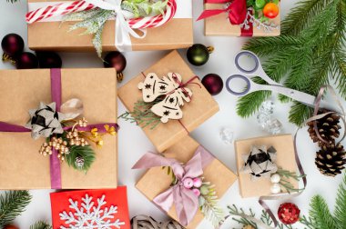 Hafif bir masanın üzerinde hediyeler, ladin dalları, makas, dekor var. Noel hediyeleri hazırlama konsepti.