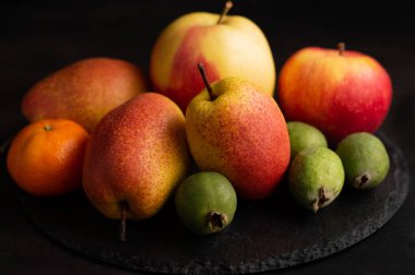 Karanlık bir arka planda, armutların bulanık bir görüntüsü, feijoa, elmalar. Meyve arkaplanı.