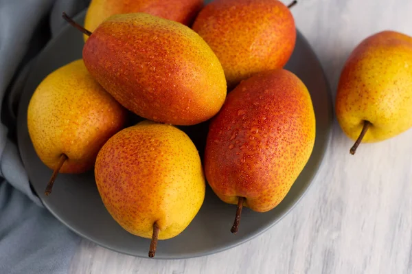 Taze, parlak armutlar arka planda gri bir tabakta. Meyve arkaplanı.