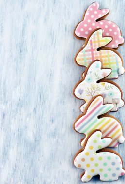 Metin yazmak için bir yeri olan gri bir arka planda, çok renkli Paskalya tavşanları şeklinde kurabiyeler. Paskalya arkaplanı..