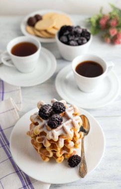 Çay içiyorum. İki fincan çayın bulanık görüntüsü, böğürtlenli Belçika waffle 'ı, beyaz kasede kurabiyeler..