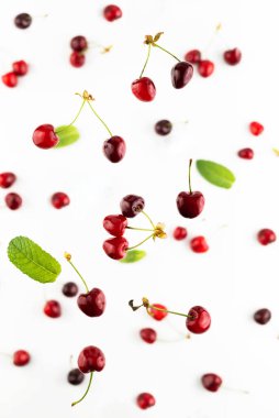 Beyaz bir arkaplanda düşen olgun kirazların bulanık görüntüsü..