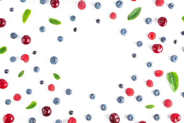 Blueberries, cherries, raspberries and mint leaves on a white background with space for text. Fruit background.