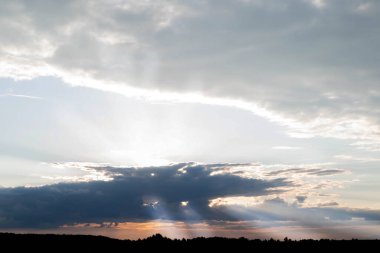 Bulutlu bir gökyüzünde gün batımının bulanık görüntüsü. Güneş ışınları bulutları delip geçiyor. Dramatik gökyüzü.
