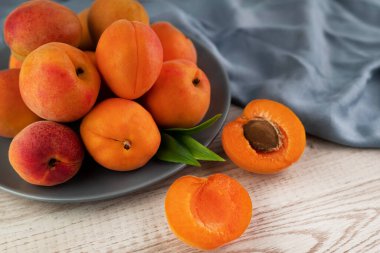 Aydınlık bir masadaki tabakta olgun kayısıların bulanık görüntüsü. Meyve arkaplanı.