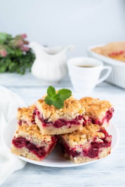 Bir tabakta vişneli turtanın bulanık görüntüsü, bir fincan kahve, bir sürahi süt, ışık masasında şekilli bir turta. Ev yapımı konsepti..