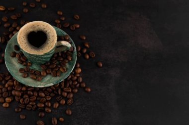 Blurred image of a cup of coffee and scattered grains on a dark background with space for writing text.Coffee love concept.
