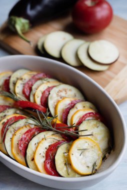 Blurred image of ratatouille in the background vegetables on a wooden board. The concept of cooking.