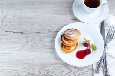 Pancakes in a plate, a cup of tea on a light table with a place for writing text.Light breakfast concept.