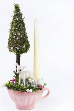 On a white background, a Christmas composition with a small Christmas tree, a deer and a candle. New Year's postcard.